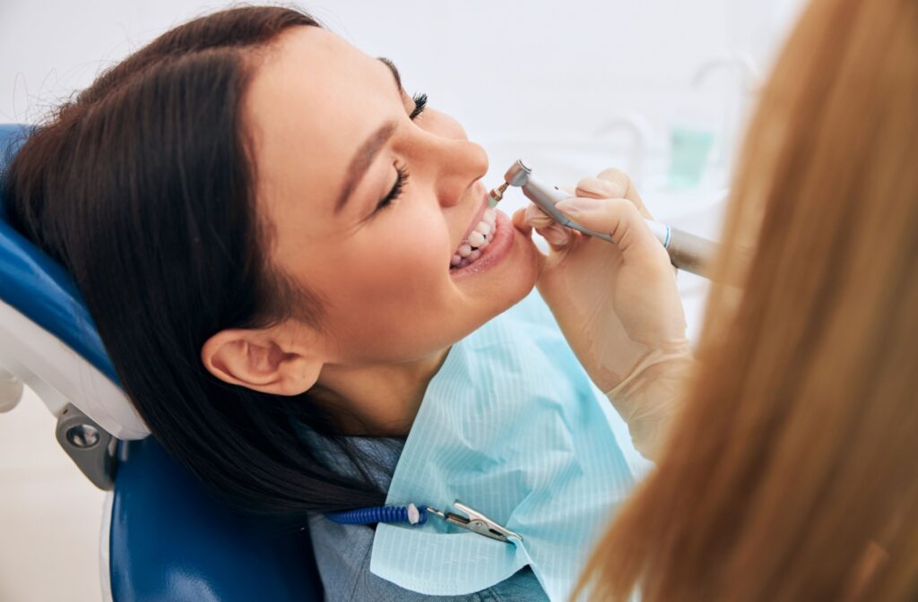 A patient smiling in a dental chair while they get their teeth cleaned